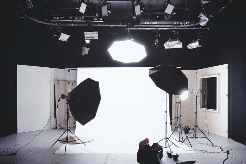 Video and audio production studio with softbox lighting, overhead lighting rig and a white cyclorama backdrop